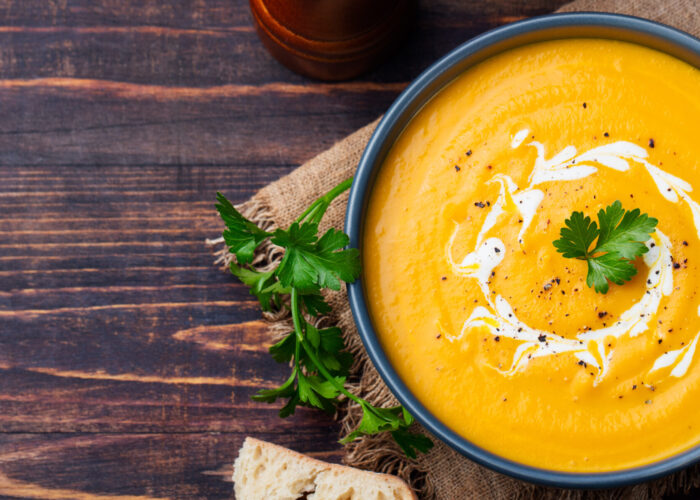 Pumpkin and carrot soup with cream and parsley on dark wooden background Top view Copy space.